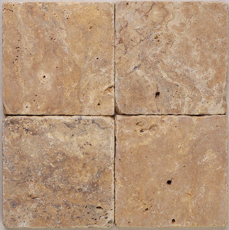 Tumbled square natural stone tiles in mixed neutral tones, laid in a soft grid across an outdoor floor. Visible variation and softened edges.