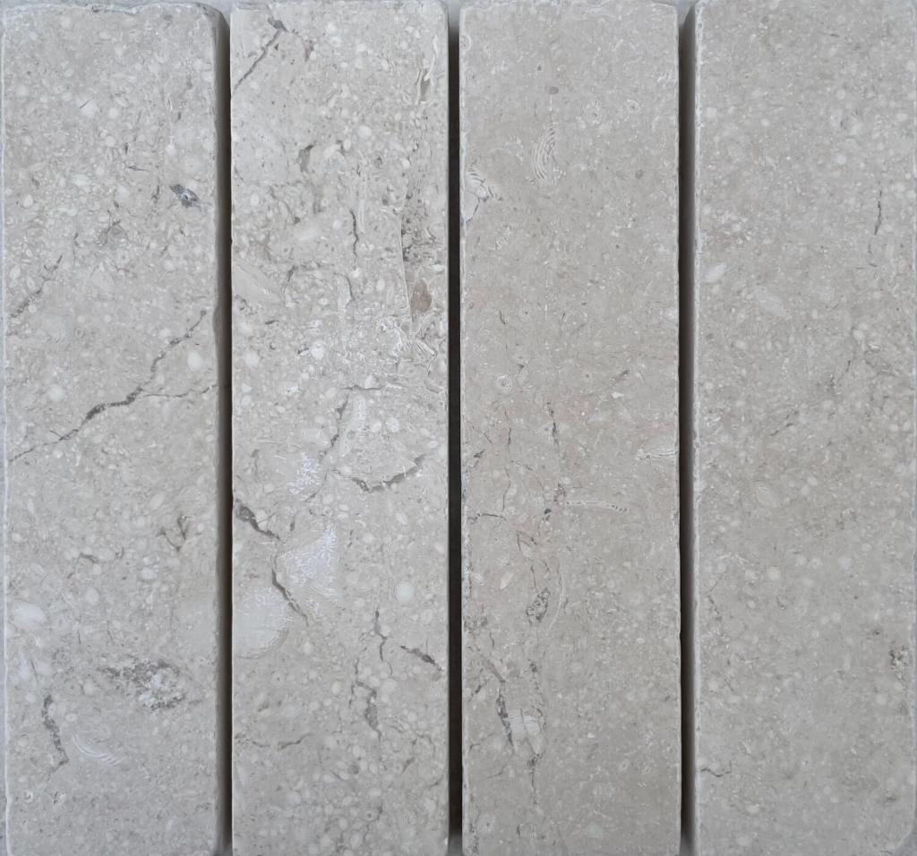 Slim tumbled natural stone batons laid in a soft neutral herringbone pattern, showing subtle surface variation and texture, suitable for indoor or outdoor use.