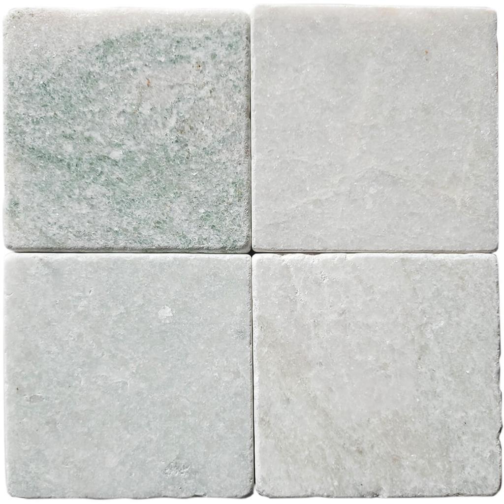 Tumbled square natural stone tiles in mixed neutral tones, laid in a soft grid across an outdoor floor. Visible variation and softened edges.