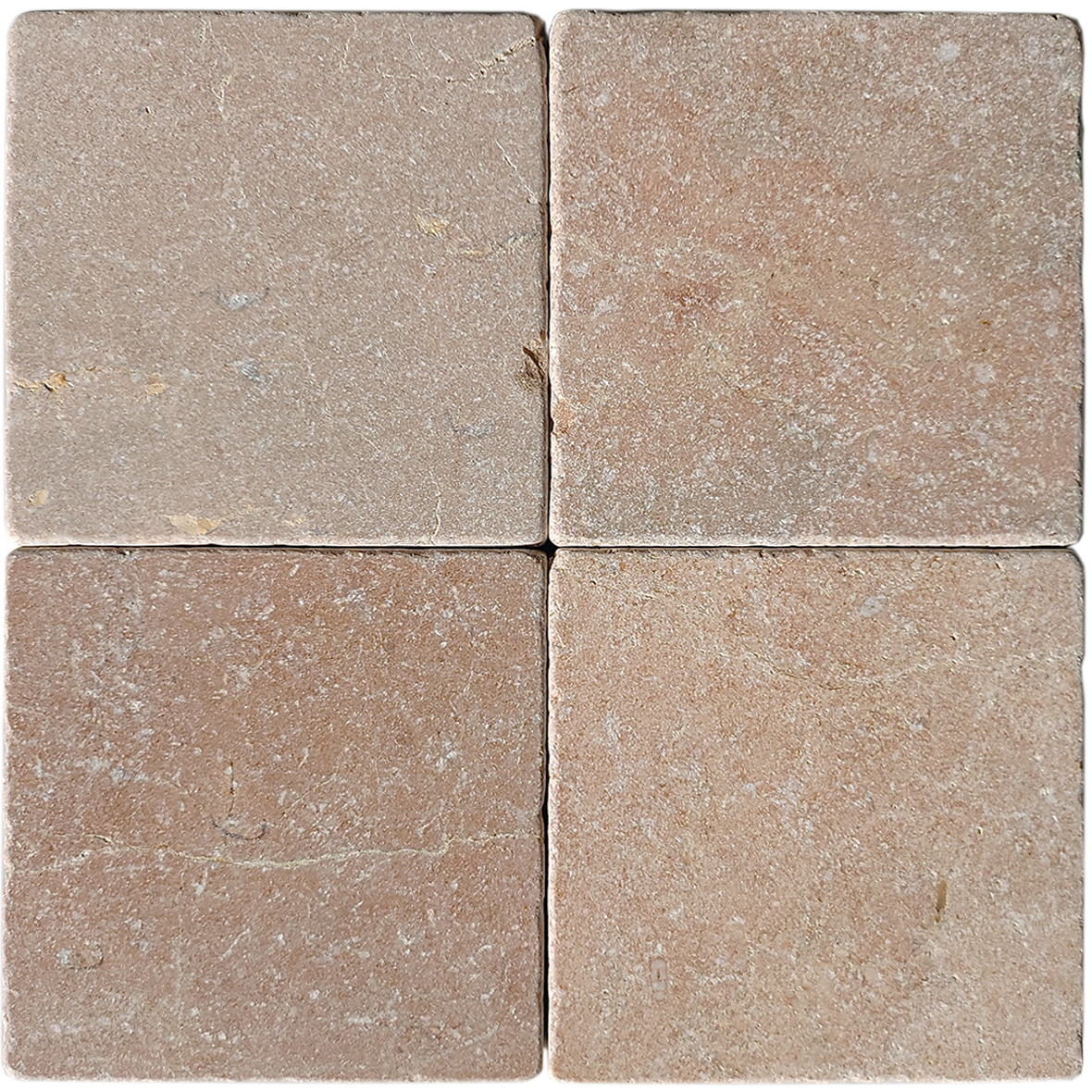 Tumbled square natural stone tiles in mixed neutral tones, laid in a soft grid across an outdoor floor. Visible variation and softened edges.