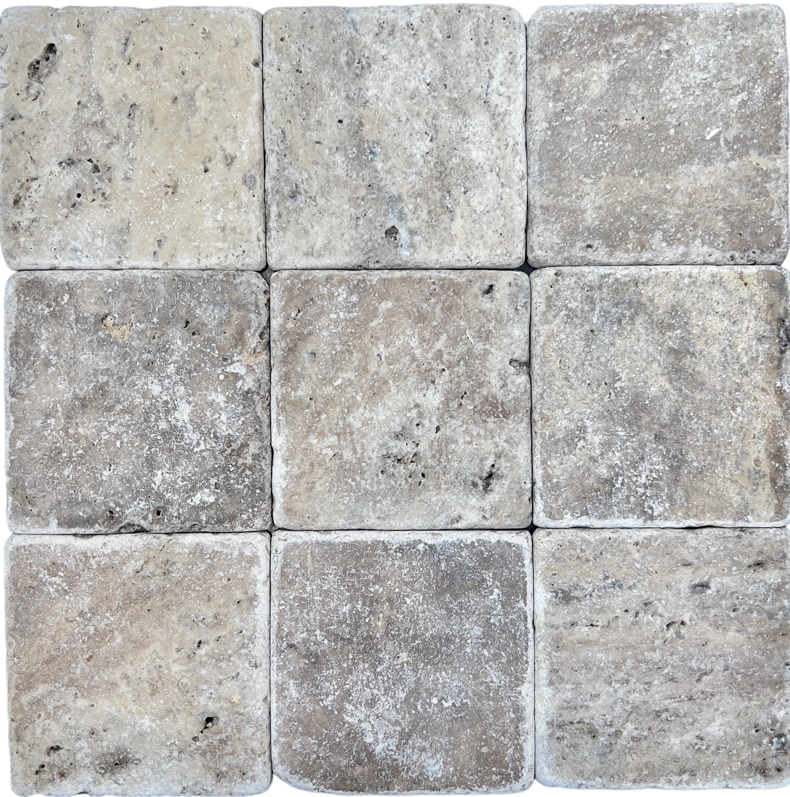 Tumbled square natural stone tiles in mixed neutral tones, laid in a soft grid across an outdoor floor. Visible variation and softened edges.