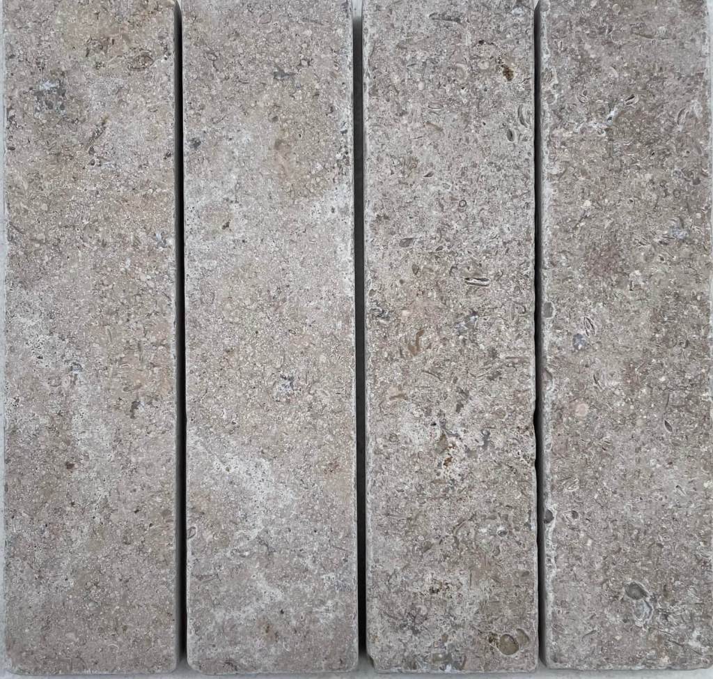Slim tumbled natural stone batons laid in a soft neutral herringbone pattern, showing subtle surface variation and texture, suitable for indoor or outdoor use.